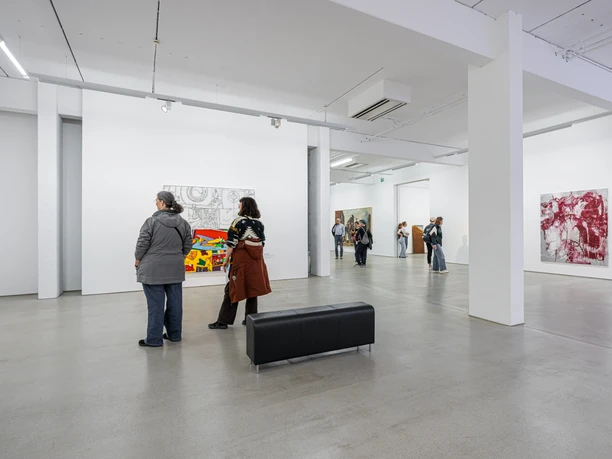 Besucherinnen und Besucher stehen in der G2 Kunsthalle und bestaunen die Gemälde an den Wänden.