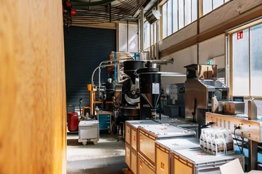 Kaffeerösterei mit Maschinen, Kaffeesäcken und verpackten Bohnen im Carlswerk