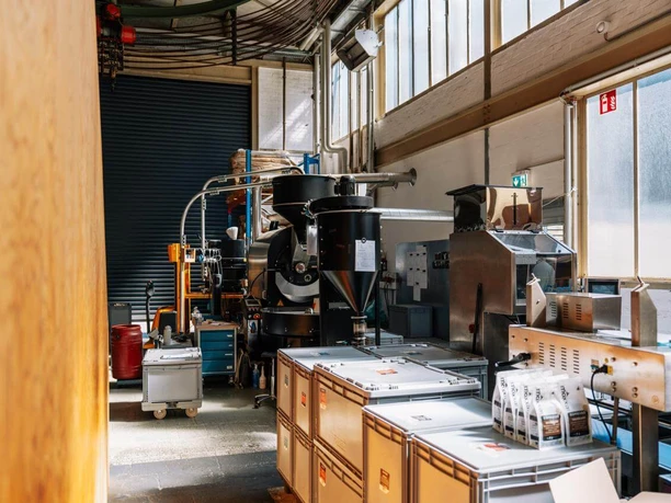 Kaffeerösterei mit Maschinen, Kaffeesäcken und verpackten Bohnen im Carlswerk