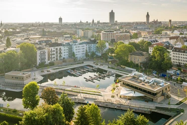 Aerial view of Leipzig's city harbor, featuring boat docks, restaurants, and the city skyline in the background.