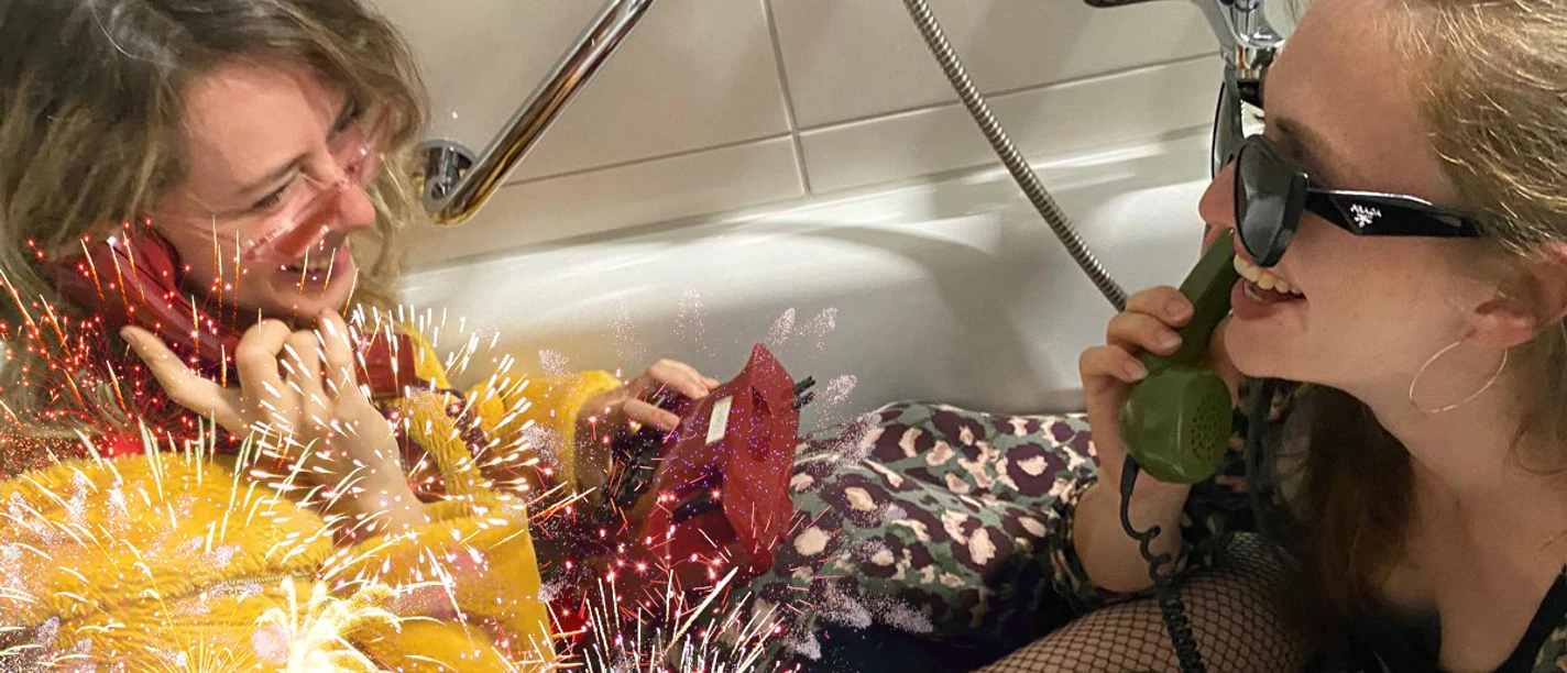 Zwei Frauen in einer Badewanne mit Telefonen, Text: Malin & Isaya, MUF '26. British English: