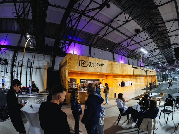 Innenansicht von The Cube Padel Köln mit Courts, Lounge und violett beleuchteter Halle