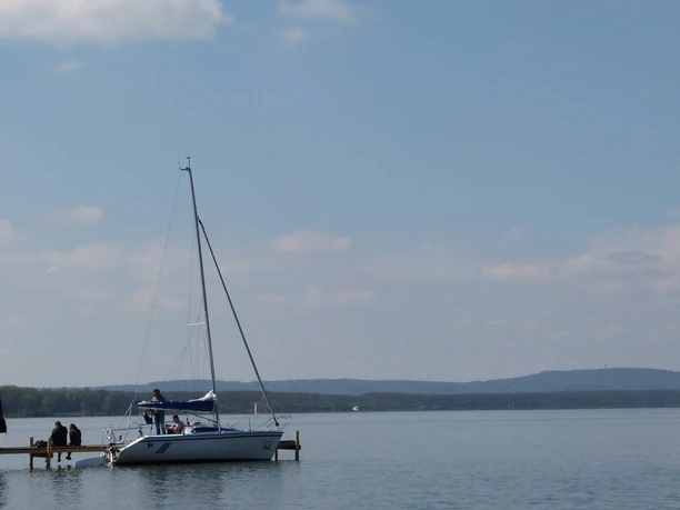 A sailing boat with a calm water surface on the shore of the Steinhuder Meer under a clear sky.
