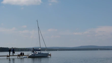 Segelboot Steinhuder Meer Een zeilboot met een rustig wateroppervlak aan de oever van het Steinhuder Meer onder een heldere hemel.