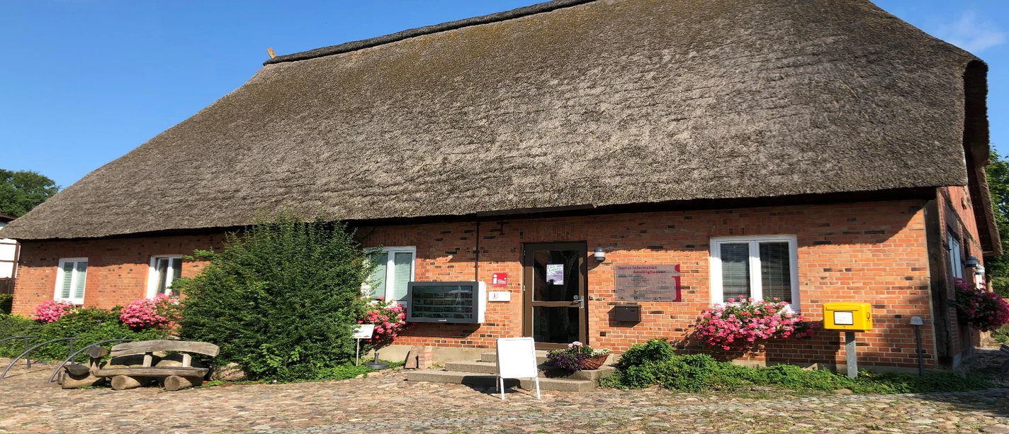 Tourist-Info Traditionelles Reetdachhaus mit roter Backsteinfassade und Eingang zur Tourist-Information.