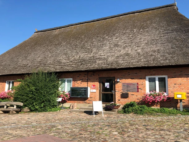 Tourist-Info Traditionelles Reetdachhaus mit roter Backsteinfassade und Eingang zur Tourist-Information.