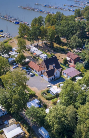 Uferweg Mardorf Luftaufnahme eines belebten Campingplatzes am Steinhuder Meer mit vielen Bootsanlegeplätzen und Grünflächen.