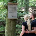 Infotafel zur Uffoburg (hitorische Wallanlage) Infotafel zur Uffoburg im Wald, mit zwei Menschen, die den Text aufmerksam lesen.