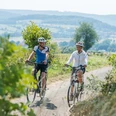 Zwei Radfahrer genießen eine Fahrt auf einem ländlichen Weg mit Blick auf die sanften Hügel von Bad Driburg.