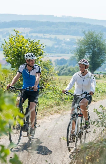 Zwei Radfahrer genieĆen eine Fahrt auf einem lƤndlichen Weg mit Blick auf die sanften Hügel von Bad Driburg.