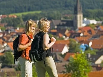 Wanderer im Naturpark Teutoburger Wald / Eggegebirge bei Bad Driburg Zwei Wanderer stehen auf einer Wiese mit Blick auf Bad Driburg, im Hintergrund bewaldete Hügel.