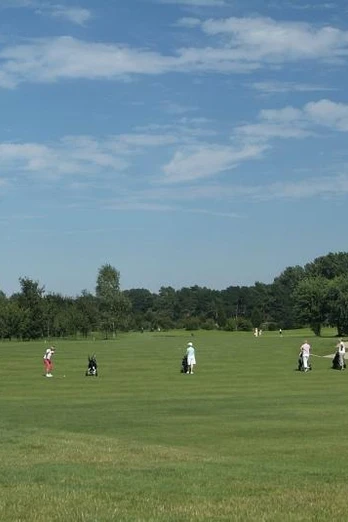Golfplatz in Peckeloh Mehrere Golfspieler auf einem grünen Fairway eines Golfplatzes unter blauem Himmel mit Wolken.