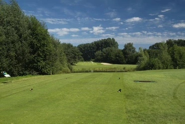 Golfplatz Peckeloh Golfplatz im Grünen mit weitläufigem Fairway, umgeben von Bäumen und blauem Himmel im Hintergrund.