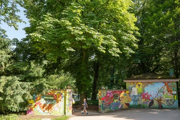 Colorful park entrance with graffiti and a child in Günthersburgpark beneath green trees