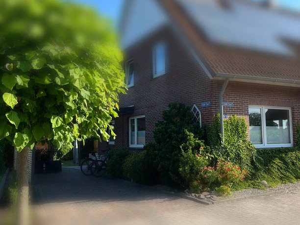 Backsteinhaus der Ferienwohnung Leni mit Garten, Baum, Auffahrt und Fahrrad.