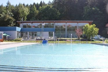 Waldschwimmbad Bad Wünnenberg Waldschwimmbad Bad Wünnenberg mit glitzerndem Wasser, umgeben von Bäumen und moderner Architektur.
