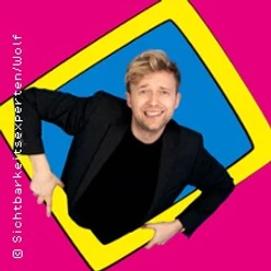 Marc Weide lehnt lachend durch einen gelben Rahmen vor pinkem Hintergrund