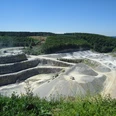 Steinbruch Düstertal Steinbruch mit terrassenförmigen Abbauflächen und umgebendem Wald unter einem klaren blauen Himmel.