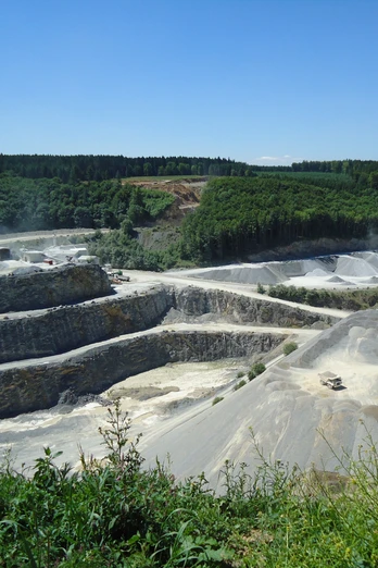 Steinbruch Düstertal Steinbruch mit terrassenförmigen Abbauflächen und umgebendem Wald unter einem klaren blauen Himmel.