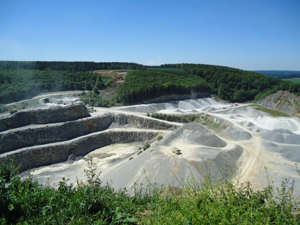 Steinbruch Düstertal Steinbruch mit terrassenförmigen Abbauflächen und umgebendem Wald unter einem klaren blauen Himmel.
