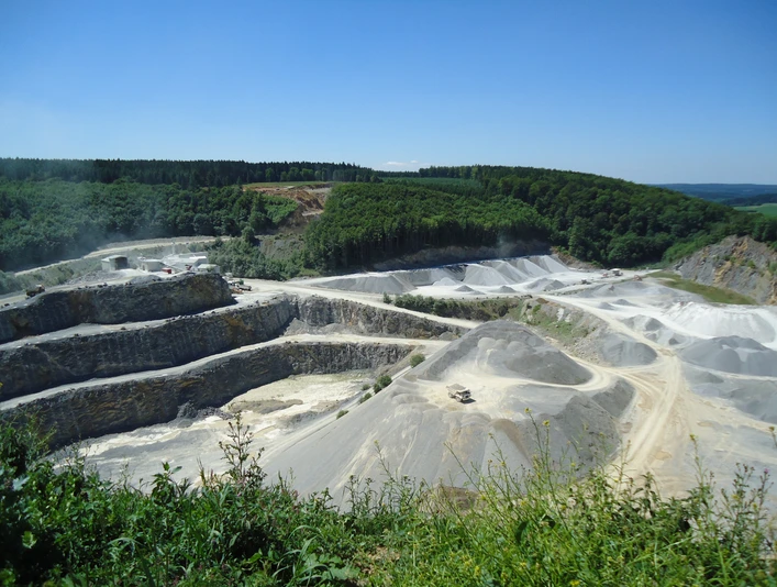 Steinbruch Düstertal Steinbruch mit terrassenförmigen Abbauflächen und umgebendem Wald unter einem klaren blauen Himmel.