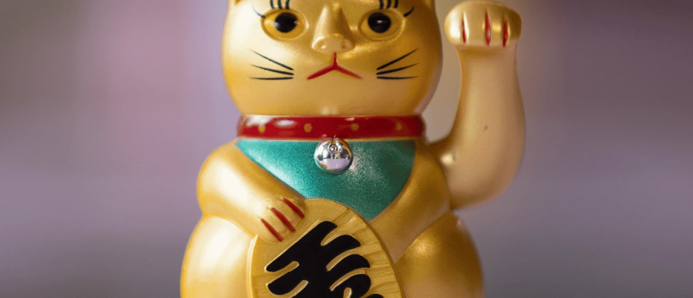 Goldene Glückskatze/Winkekatze auf einem Ausstellungssockel