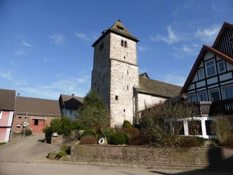 Steinerne Georgskirche in Amelunxen, umgeben von Wohnhäusern.