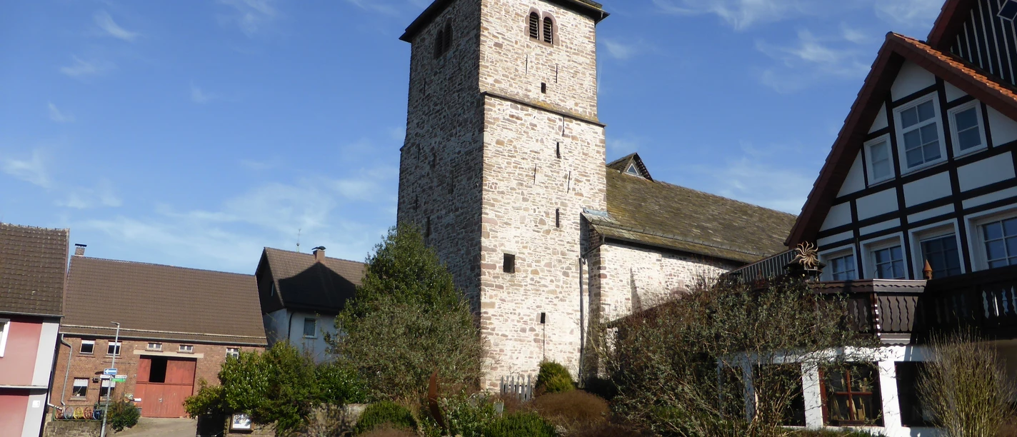 Steinerne Georgskirche in Amelunxen, umgeben von Wohnhäusern.