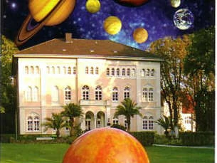 "Der Planetenweg" Bad Lippspringe Ein großes, historisches Gebäude wird von einer fantasievollen Darstellung des Sonnensystems überragt.