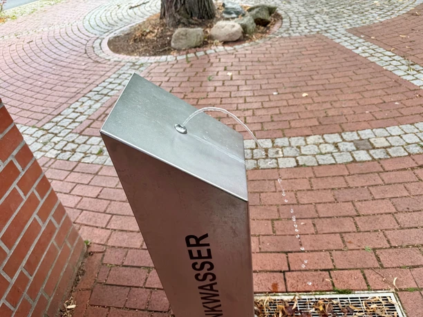 A drinking fountain with a water jet on the paved market square in Steyerberg.
