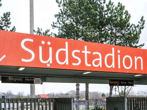 Eingang des Kölner Südstadions mit rotem Schriftzug, Toren und Blick ins Stadion