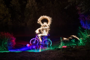 Person auf einem Fahrrad bei Nacht mit leuchtenden Funken