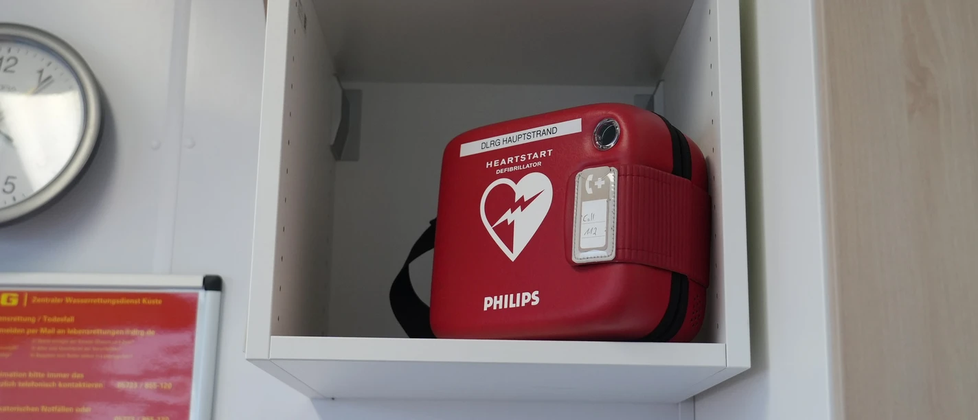 Defibrillator DLRG Hauptstrand Ein Defibrillator in einem Regal an der Wand