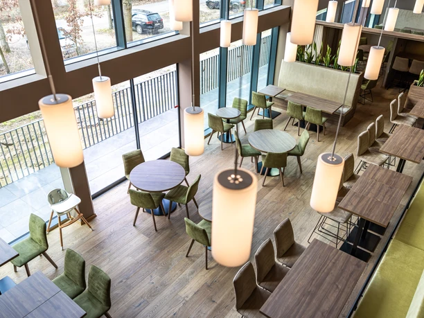 Moderner Frühstücksraum im Platzhirsch Living mit großen Fenstern und grünen Sitzplätzen