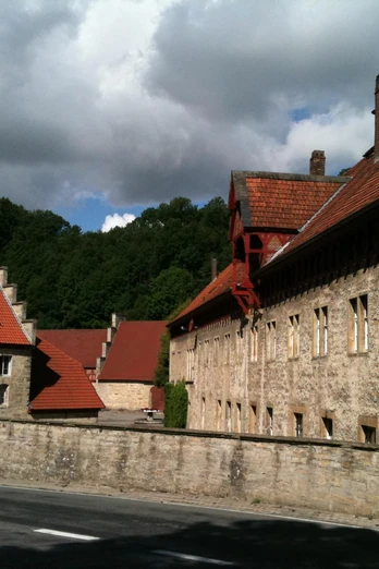 Historische Klosteranlage Gut Böddeken mit roten Ziegeldächern, umgeben von dichter Waldlandschaft.