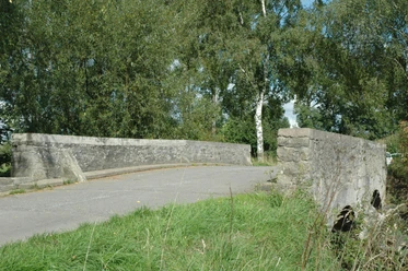 Heubachbrücke bei Eichholz Steinerne Brücke überquert einen kleinen Bach, umgeben von grüner Vegetation und sanftem Tageslicht.