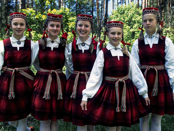 fünf Kindern in traditionellem Gewand, im Hintergrund ein Wald, sie lachen in die Kamera