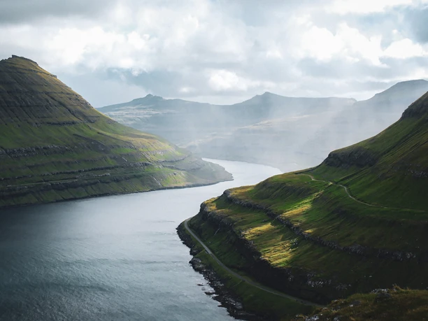 ruhige Natur, ein Fluss schlengelt sich zwischen zwei Gebirgen, es ist nebelig