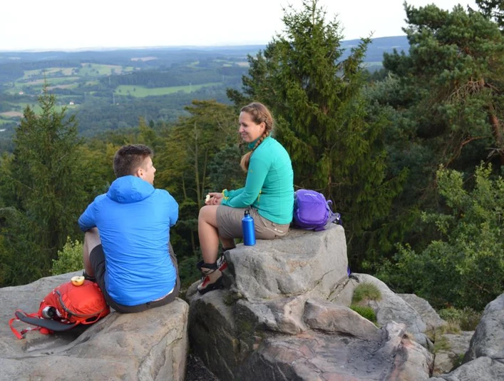 Lippische Velmerstot Zwei Personen sitzen auf Felsen im Lippischen Velmerstot, umgeben von bewaldeter Landschaft.