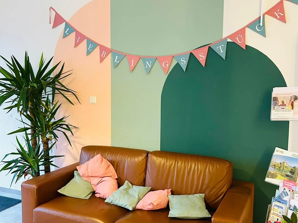 Einladende Sitzecke im Café Lieblingsstück mit Ledersofa, bunten Kissen und Wimpelkette