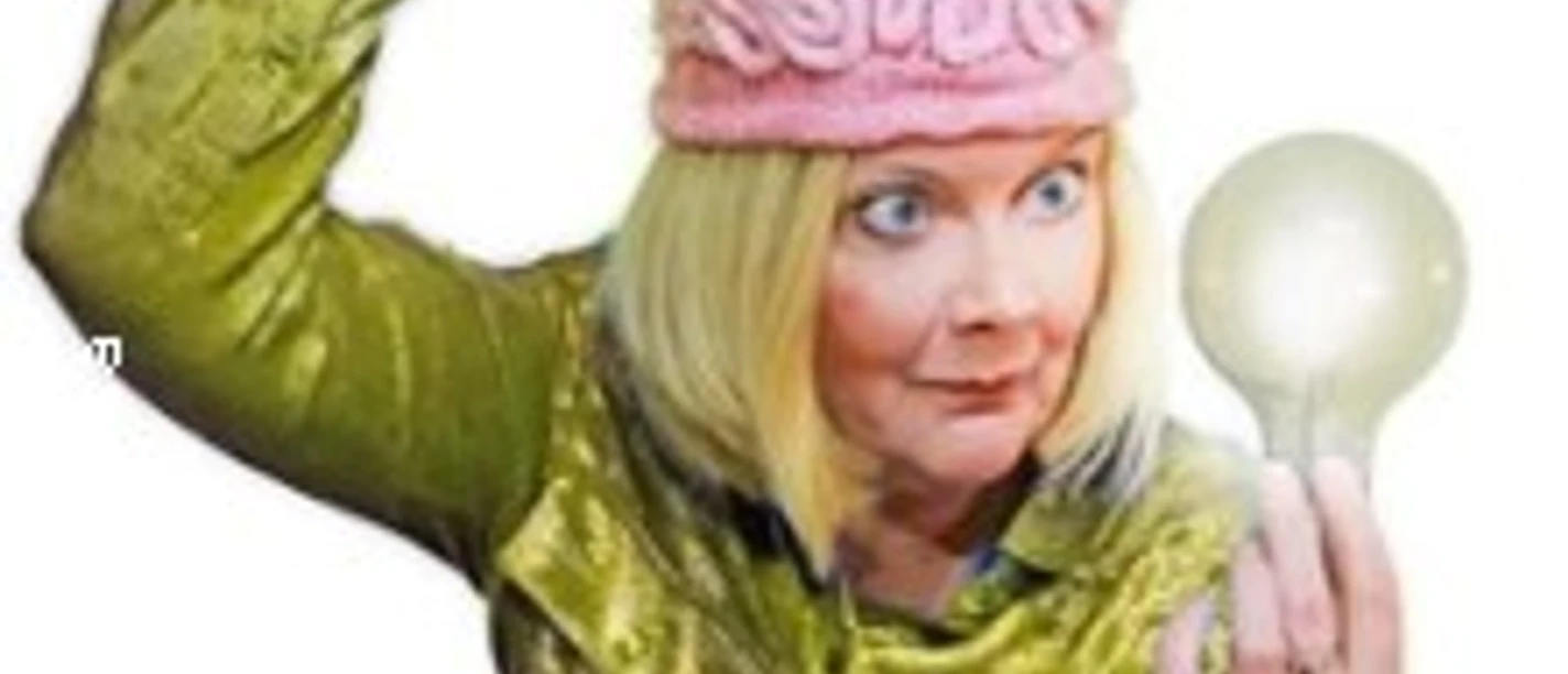 Blonde Frau mit pinker Gehirn-Mütze hält eine Glühbirne und blickt schelmisch.