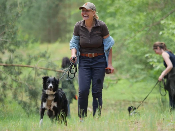 Hundewanderung 1.JPG Du siehst eine lachende Hundeführerin mit Hund in üppiger Vegetation.