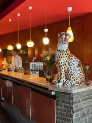 Interior of the Elektra Music Bar, featuring a bar, warm hanging lamps, and a large cheetah figurine