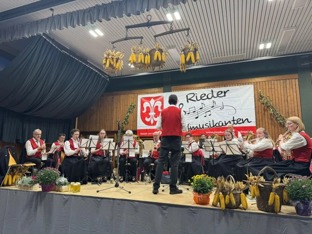 Bild der Rieder Dorfmusikanten sitzend auf der Bühne Bild der Rieder Dorfmusikanten sitzend auf der Bühne