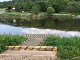 Ein Kanuanleger am Fluss, mit Fähranlegestelle und Gastronomiebetrieb auf der anderen Flussseite.