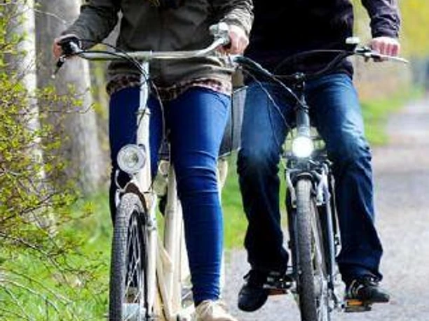 Flyer der LGS-Route Zwei fröhliche Radfahrer auf einem Waldweg mit Plakat der Landesgartenschau-Route.