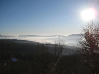 Blick über neblige Täler und bewaldete Hügel bei Sonnenaufgang vom Winterberg-Wanderweg.