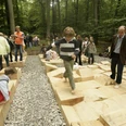 Parkkettinsel Kinder und Erwachsene erkunden barfuß geometrisch gestaltete Holzplattformen in einem Waldgebiet.