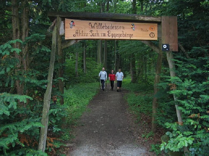 Aktiv-Park im Eggegebirge Eingang zum Aktiv-Park im Eggegebirge, mit drei Personen auf einem Waldweg beim Nordic Walking.