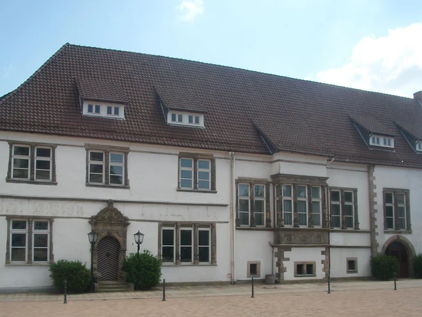 Adelshof mit weißer Fassade, roten Dachziegeln und steinernen Fensterrahmen